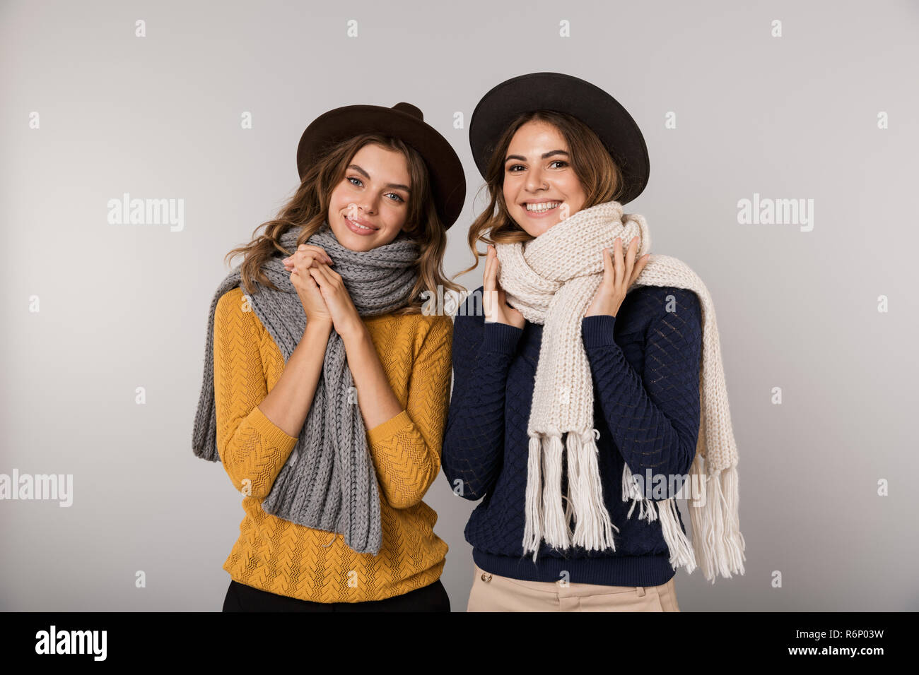 Immagine delle due donne allegro indossare cappelli e sciarpe sorridente in telecamera isolate su uno sfondo grigio Foto Stock