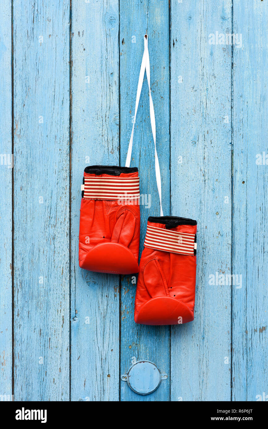 Una coppia di cuoio rosso guantoni da pugilato appeso su un cordone bianco Foto Stock
