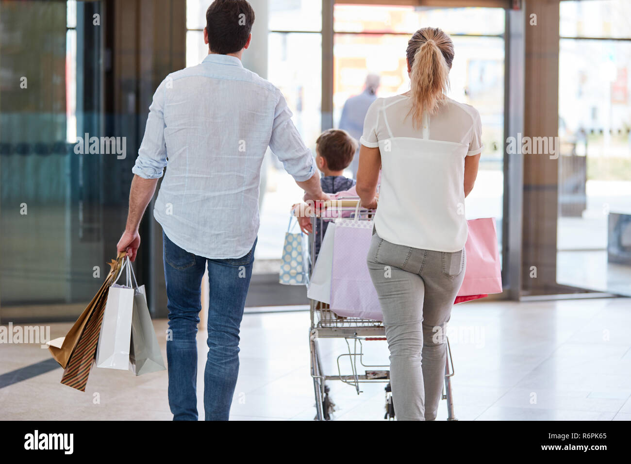Famiglia spinge i loro acquisti nel carrello per l'uscita del centro commerciale Foto Stock