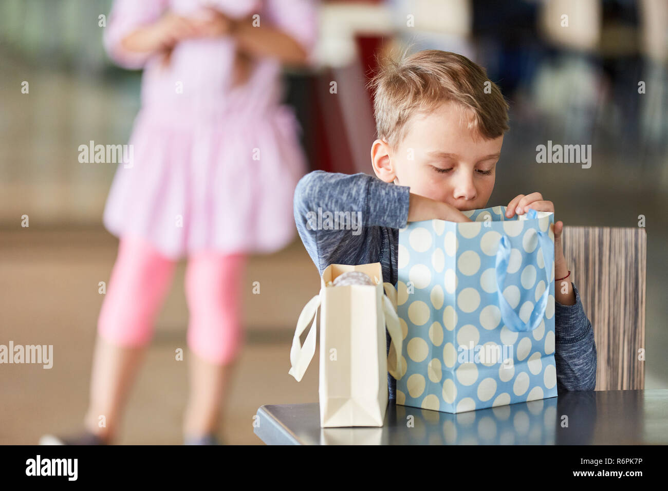 Little Boy curiosamente sembra in una borsa per lo shopping nel centro commerciale per lo shopping Foto Stock