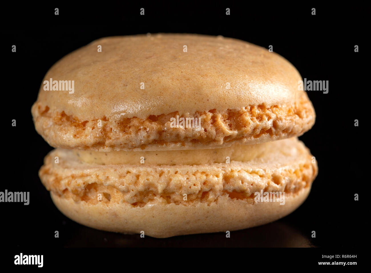 Unico dolce marrone macaron su sfondo nero Foto Stock