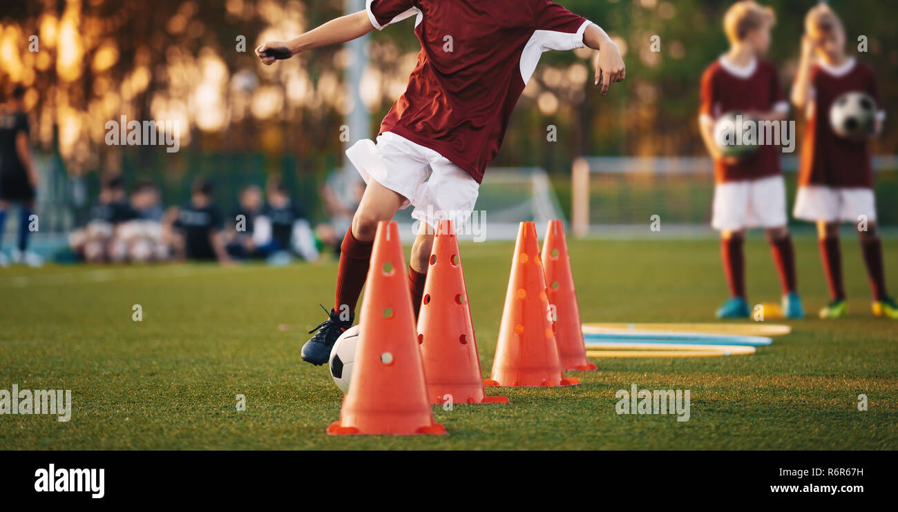 Schemi calcio: il trapano di slalom. Il calcio giovanile pratica  esercitazioni. I giovani giocatori di calcio sulla formazione del passo.  Soccer slalom trapano a cono. Ragazzo in rosso soccer Foto stock -