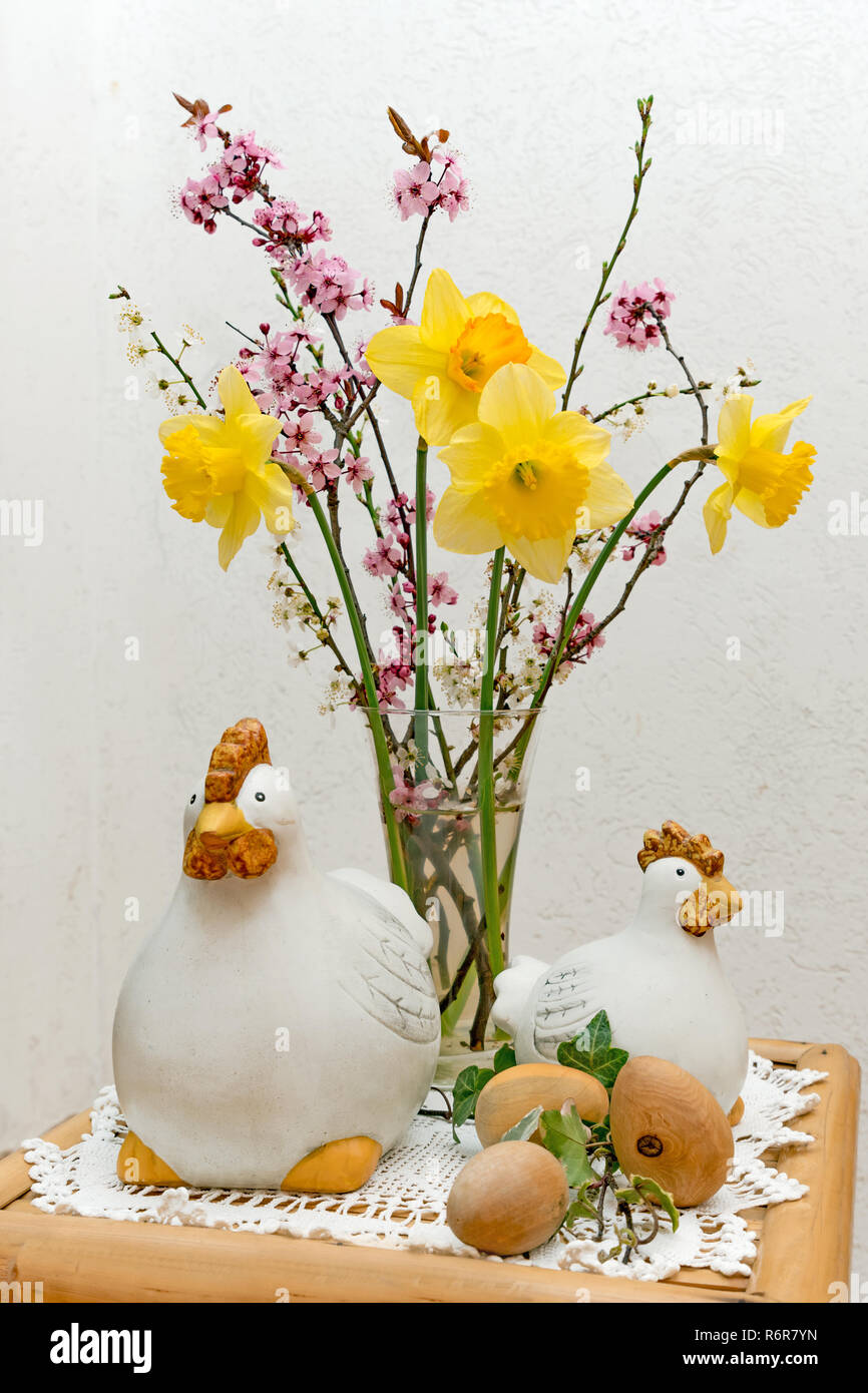 Bouquet con decorazione di pasqua consistente della figurina di pollo e uova di legno si erge su un tavolo Foto Stock