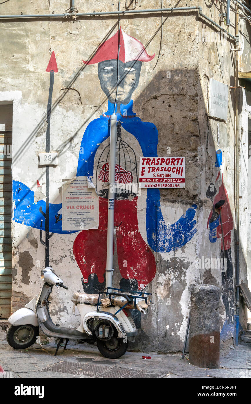 Un vecchio scooter parcheggiata da una parete affresco di Pulcinella, una figura popolare nella Commedia dell'arte e teatro di strada a partire dal XVII sec. in quarti Foto Stock