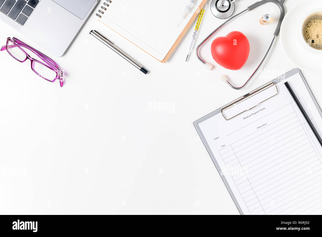 Vista superiore del medico scrivania con uno stetoscopio e cuore rosso, caffè e laptop. Vista da sopra con copia spazio, laici piana. Foto Stock