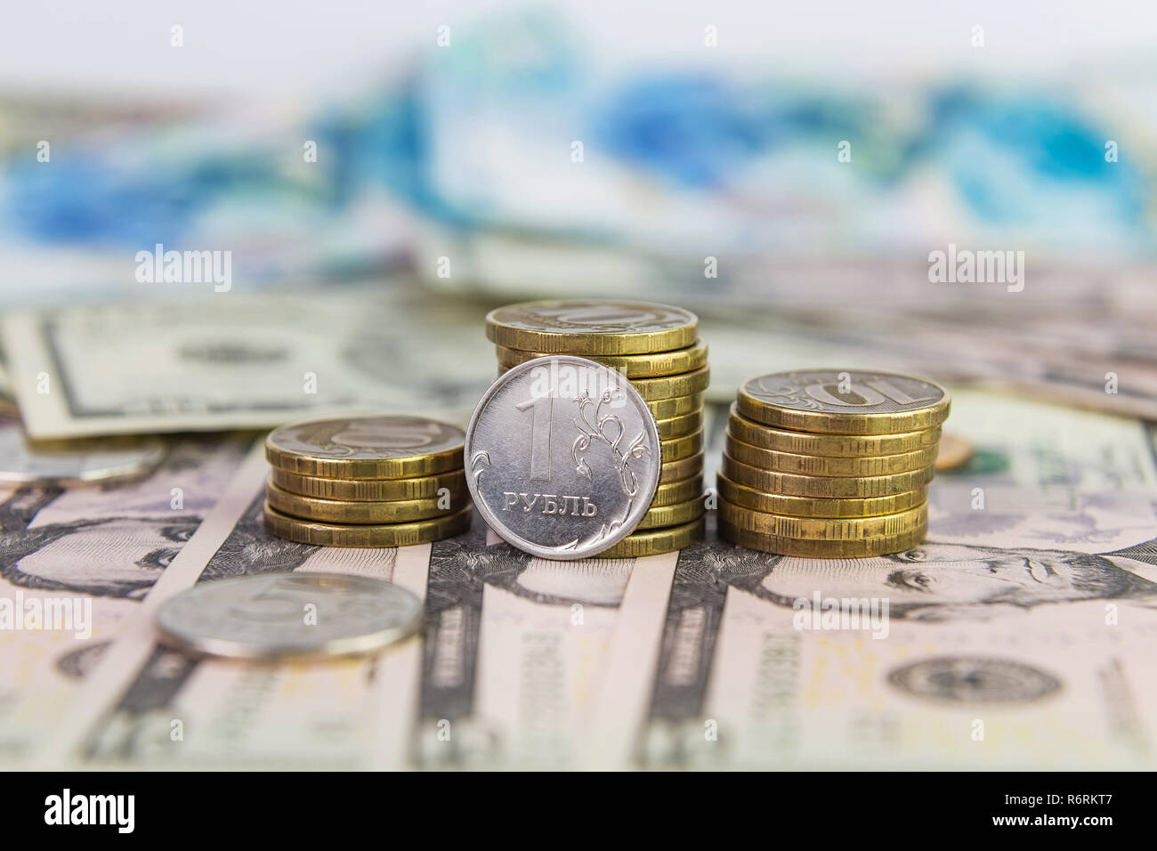 Un rublo contro lo sfondo di una pila di monete 10 rubli giacente su fatture del dollaro Foto Stock