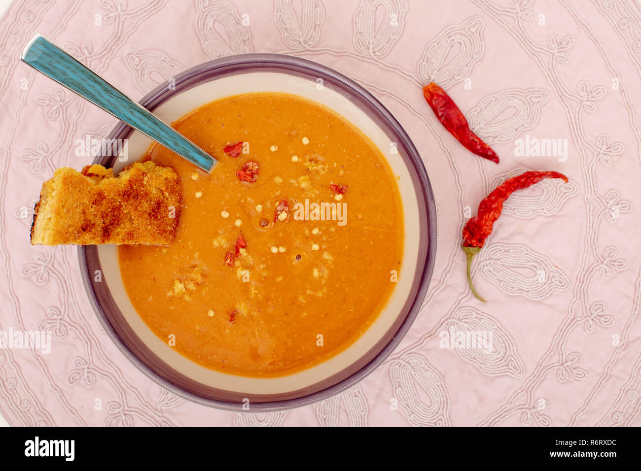 Zuppa di lenticchie nella ciotola con freschi di forno il pane di mais e red hot chili peppers sul tessuto di vista da sopra Foto Stock