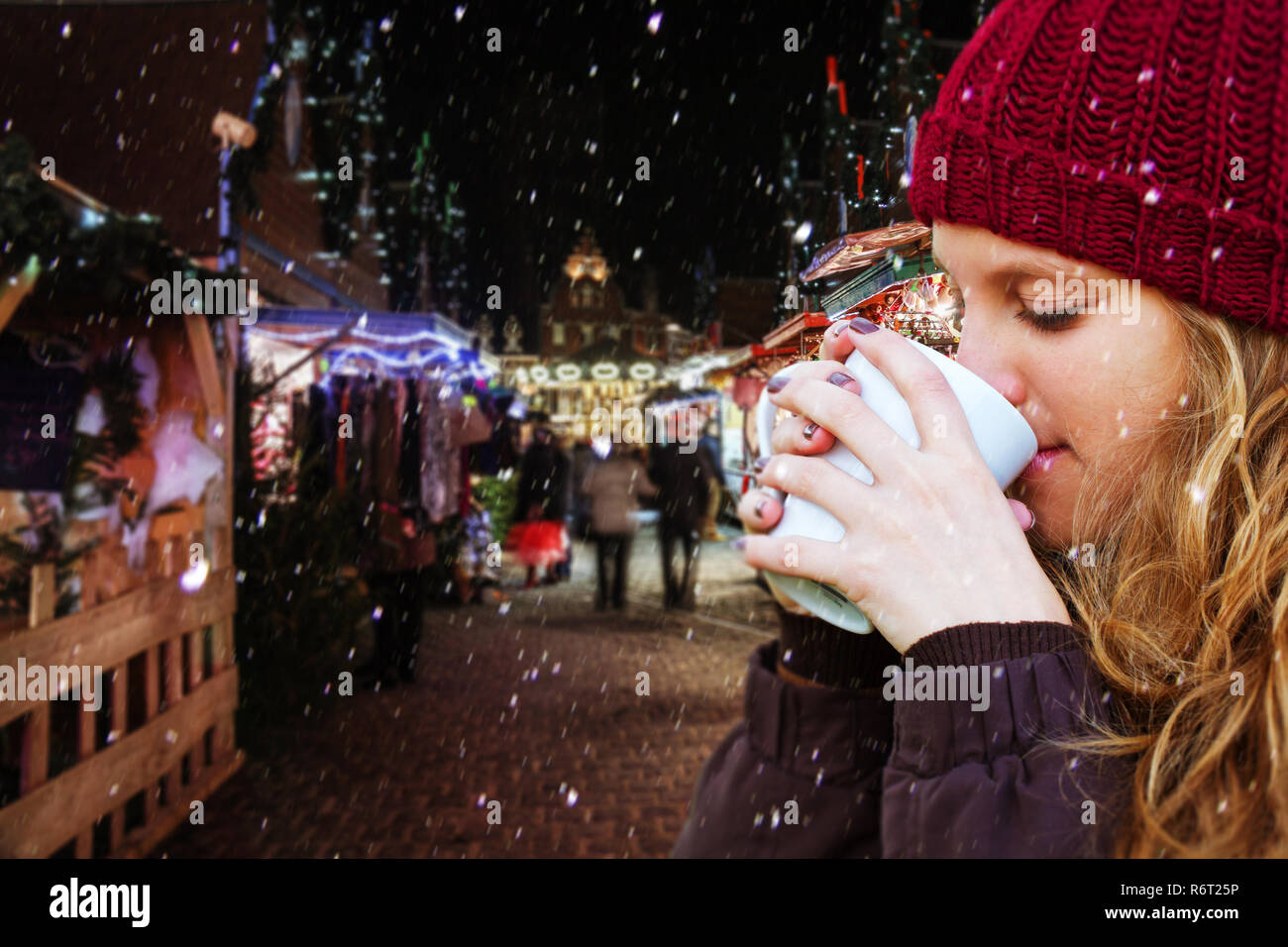 Giovane donna di bere una bevanda calda sul mercato di natale Foto Stock
