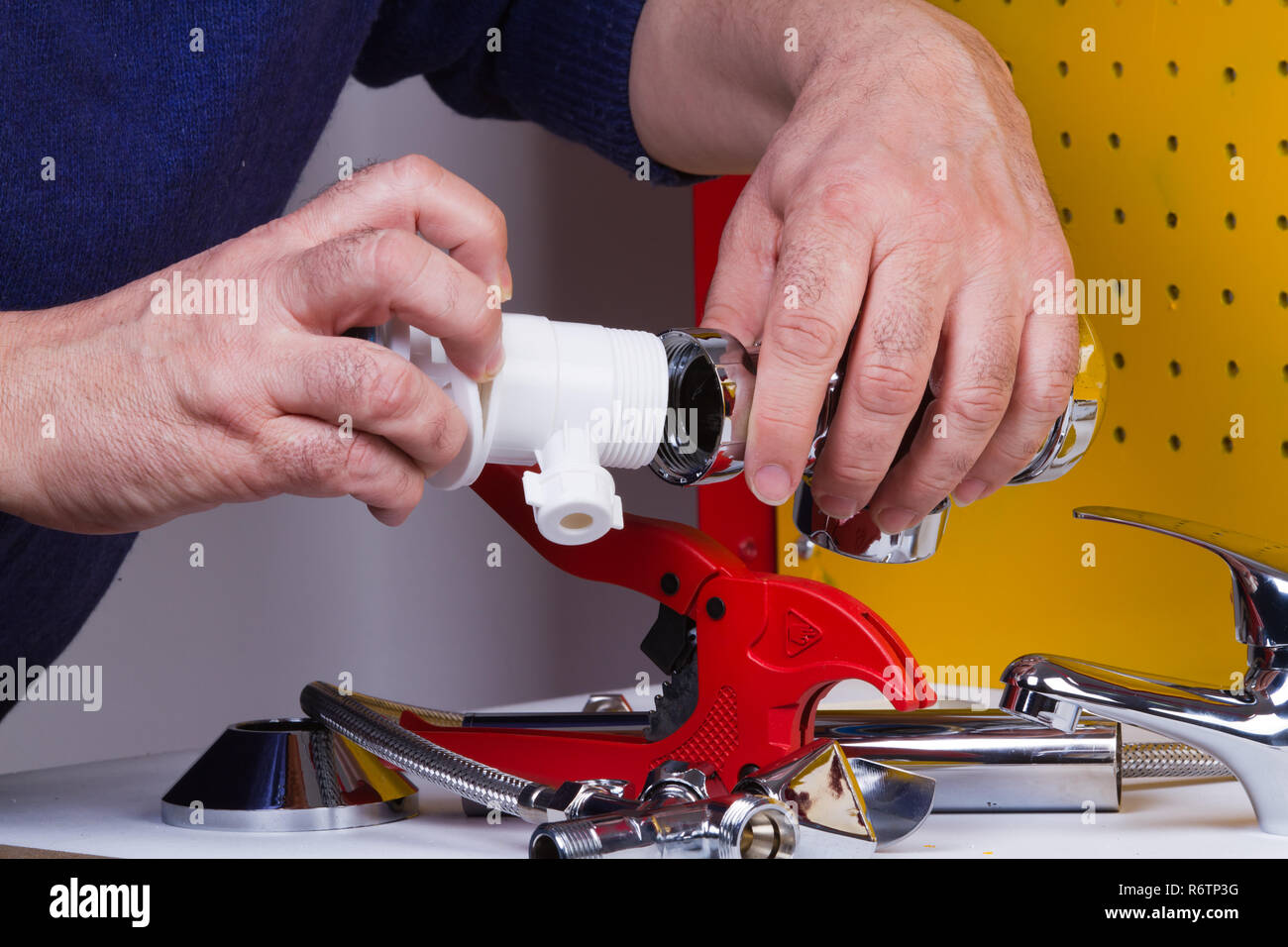 Plumber al lavoro sul suo banco di lavoro per fissare i tubi Foto Stock