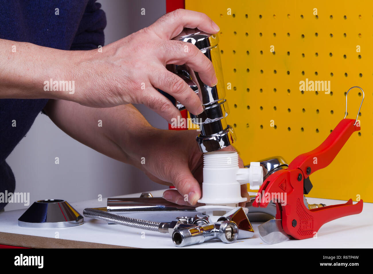 Plumber al lavoro sul suo banco di lavoro per fissare i tubi Foto Stock