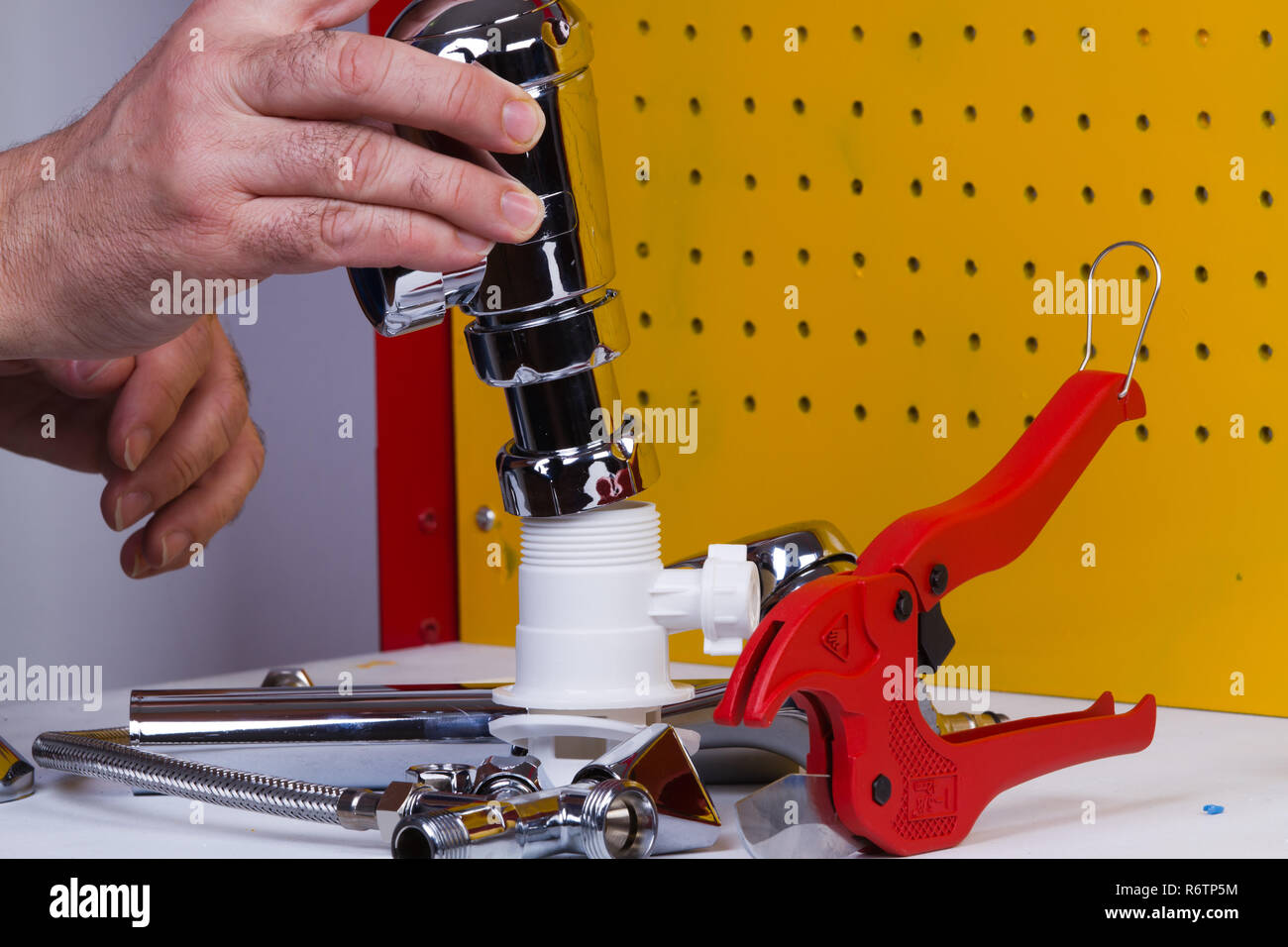 Plumber al lavoro sul suo banco di lavoro per fissare i tubi Foto Stock