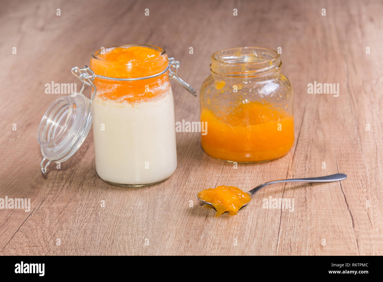Yogurt fatto in casa e in casa confettura di pesche sul tavolo di legno in un barattolo di vetro Foto Stock