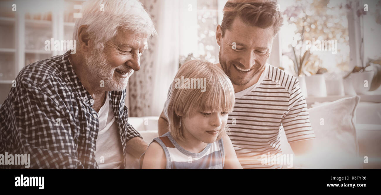 Ragazzo con tavoletta digitale con suo padre e suo nonno in salotto Foto Stock