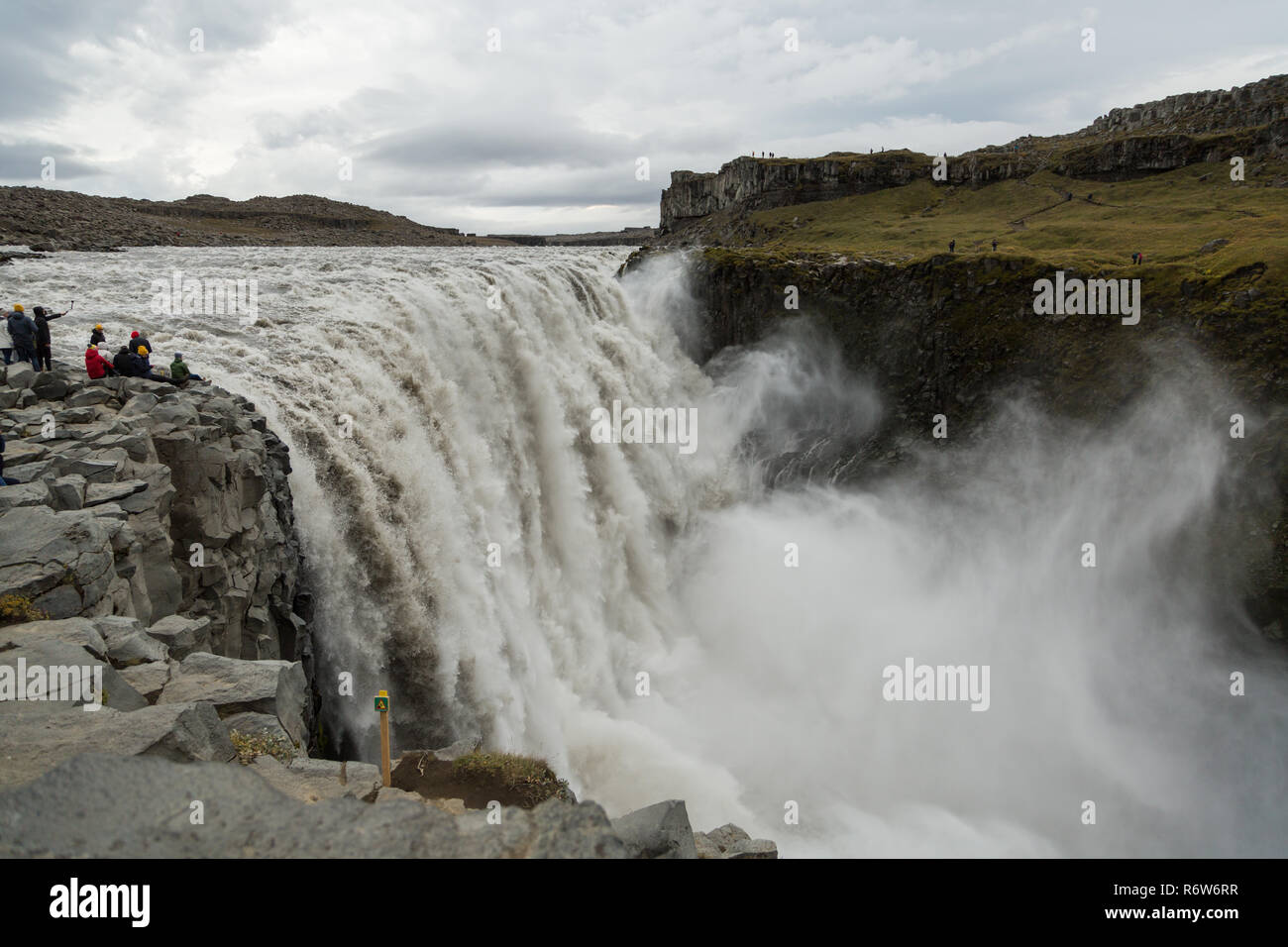 I turisti ottenere pericolosamente vicino al bordo della cascata di Dettifoss in Islanda prendendo selfies e che posano per una foto Foto Stock