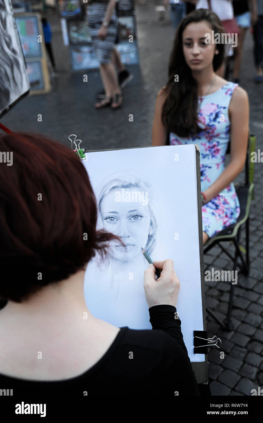 Artista femminile disegno il ritratto di una giovane dai capelli scuri, donna in Piazza Navona, una piazza famosa tra gli artisti di strada, i fornitori e gli artisti interpreti o esecutori, Roma Foto Stock