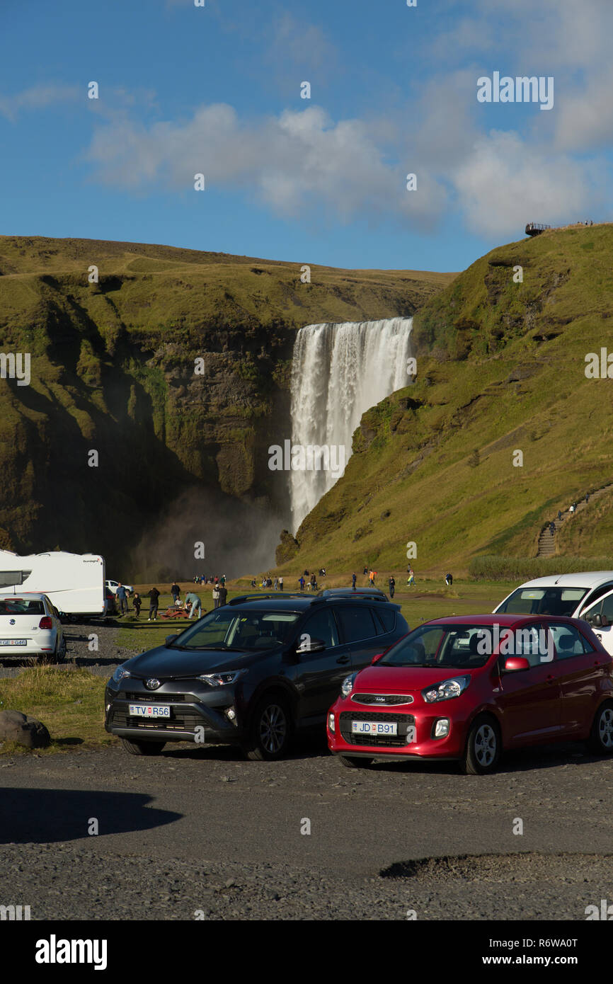 Il parcheggio auto full up con i turisti alla cascata Skogafoss, Skogar, Islanda Foto Stock
