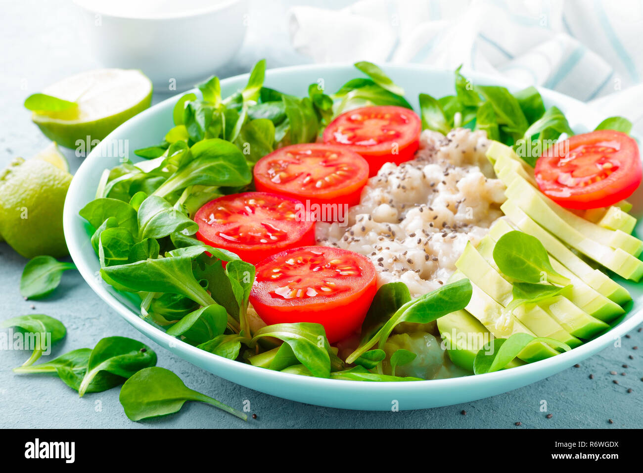 Farina di avena porridge con avocado e insalata di verdure fresche di pomodori e lattuga. Dieta sana prima colazione Foto Stock