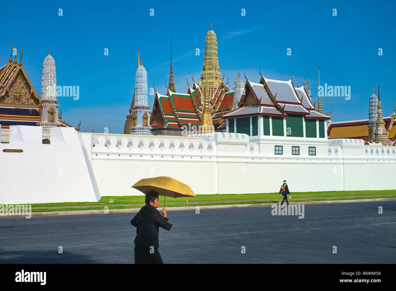 I pedoni a camminare lungo la impressionante skyline di Wat Phra Kaew (Gaew) e il Grand Palace a Bangkok, Thailandia, il paese il più venerato tempio Foto Stock