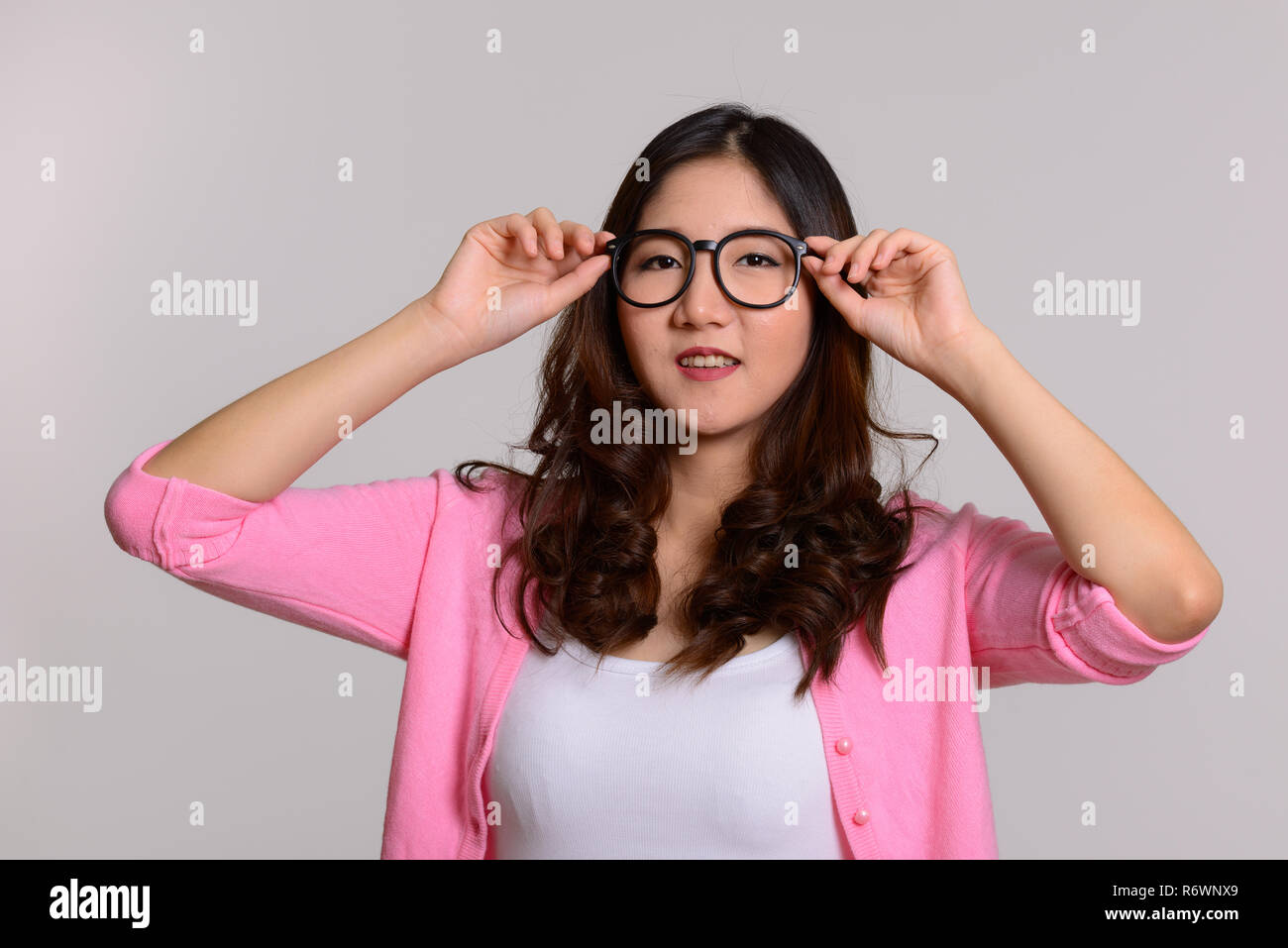 Felice giovane donna asiatica con le mani su un occhiale Foto Stock