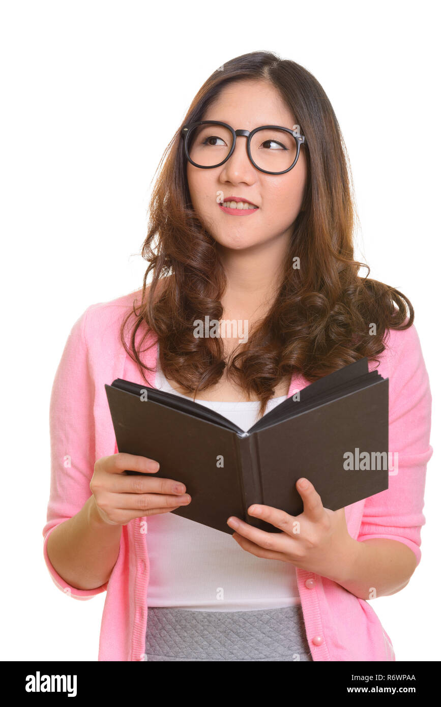 Felice giovane donna asiatica azienda libro mentre pensando Foto Stock