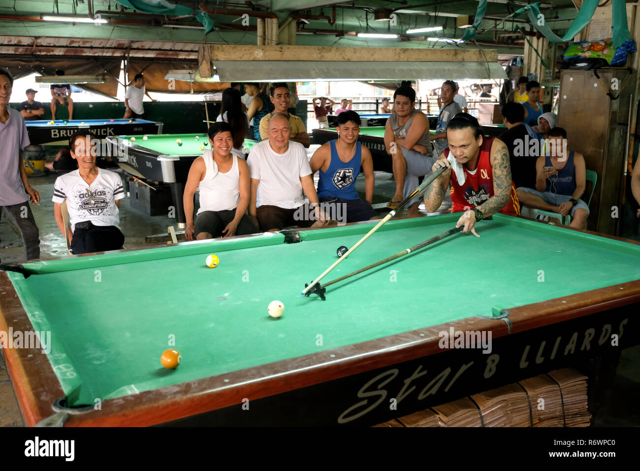 Gli uomini di giocare a biliardo in un tavolo da biliardo in un pubblico gambling hall. La città di Quezon, Metro Manila, Filippine Foto Stock