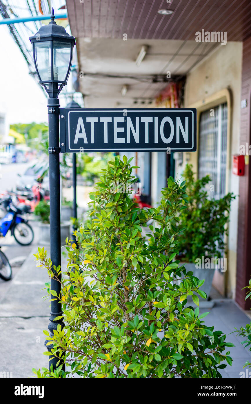 Un casuale attenzione decorativa segno attaccato a una lampada posta su un marciapiede in città. Foto Stock