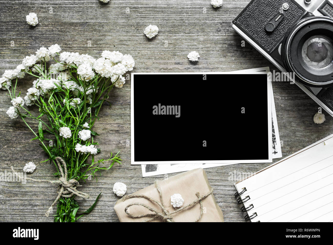 Vintage fotocamera retrò con blank foto telaio bianco e bouquet di fiori con notebook rivestito e confezione regalo. vista dall'alto. mock up Foto Stock