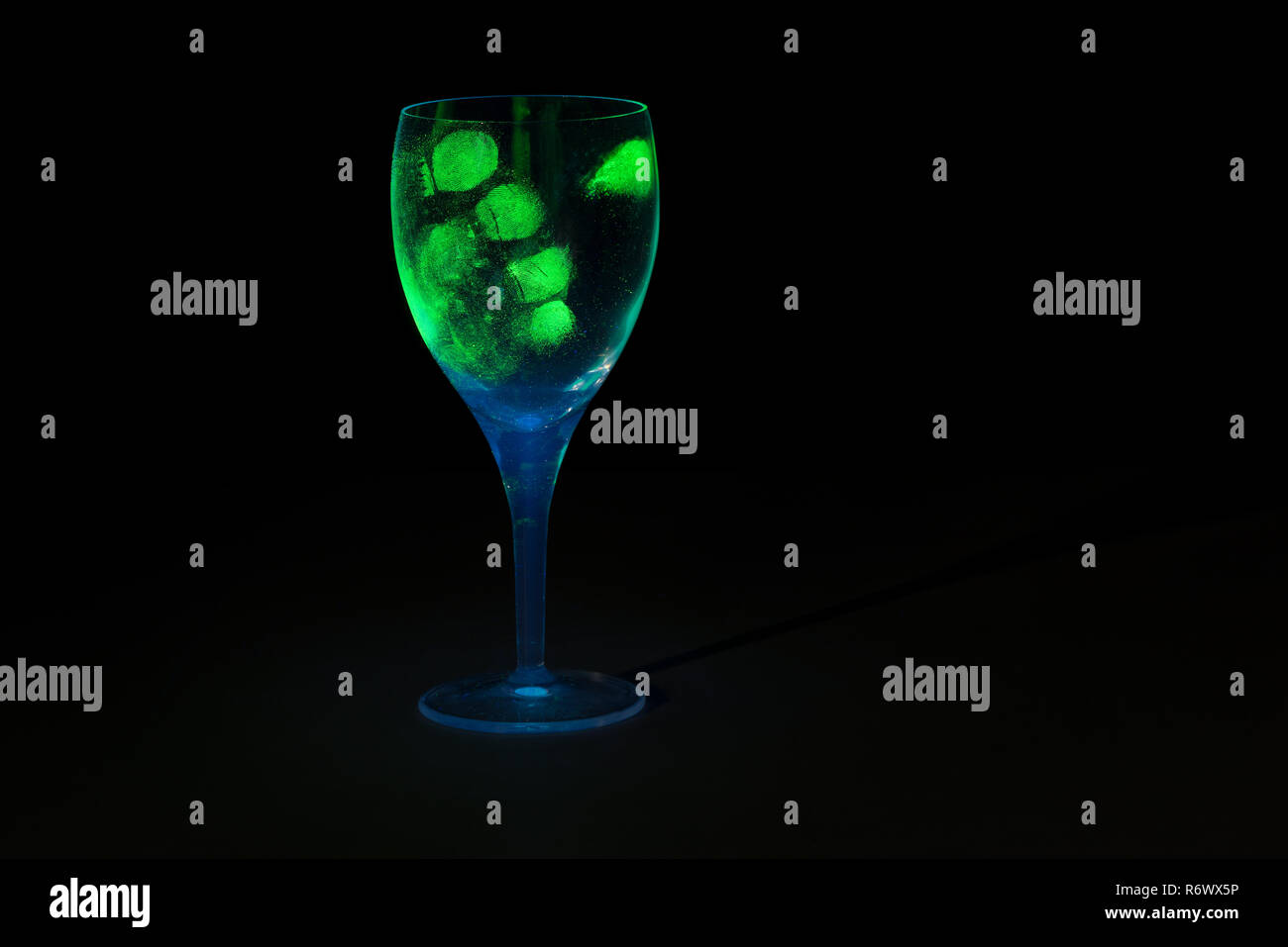 Pollice stampare le impronte digitali sul bicchiere di vino che mostra fino sotto blacklight luce ultravioletta come prove forensi di identità per il sospetto Foto Stock