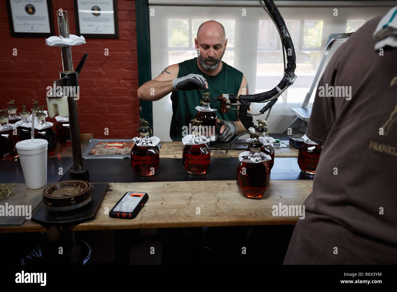 Uomo di applicare cera di tenuta per una bottiglia di Blanton di Borbone sulla linea di imbottigliamento a Buffalo Trace Distillery, Francoforte, Kentucky Foto Stock