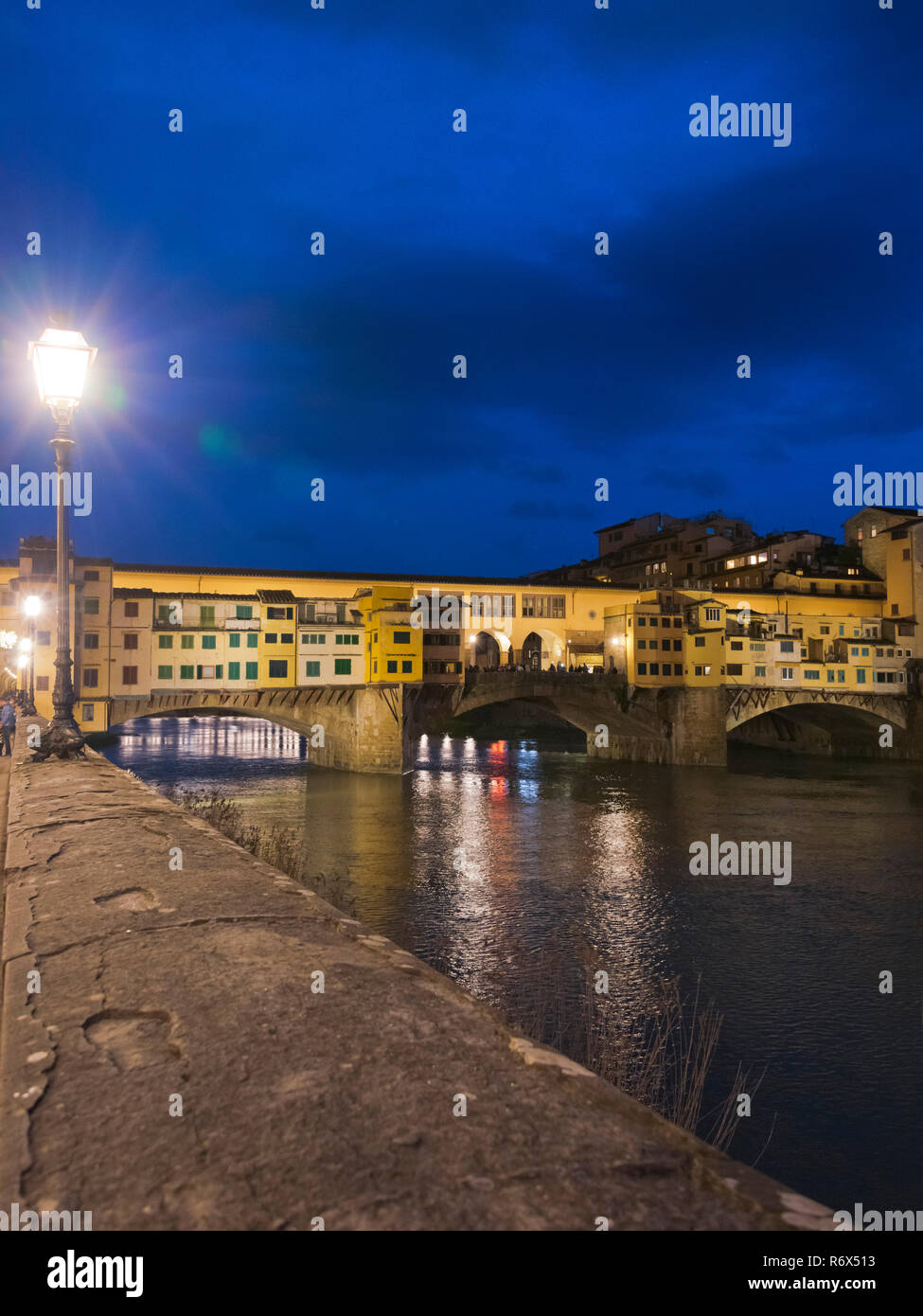 Vista verticale del Ponte Vecchio illuminata di notte a Firenze, Italia. Foto Stock