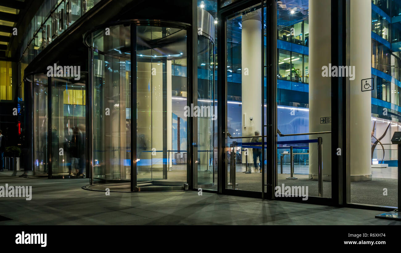 Il flusso di persone che passano attraverso la porta girevole dell'ufficio moderno edificio alla fine di una giornata di lavoro Foto Stock