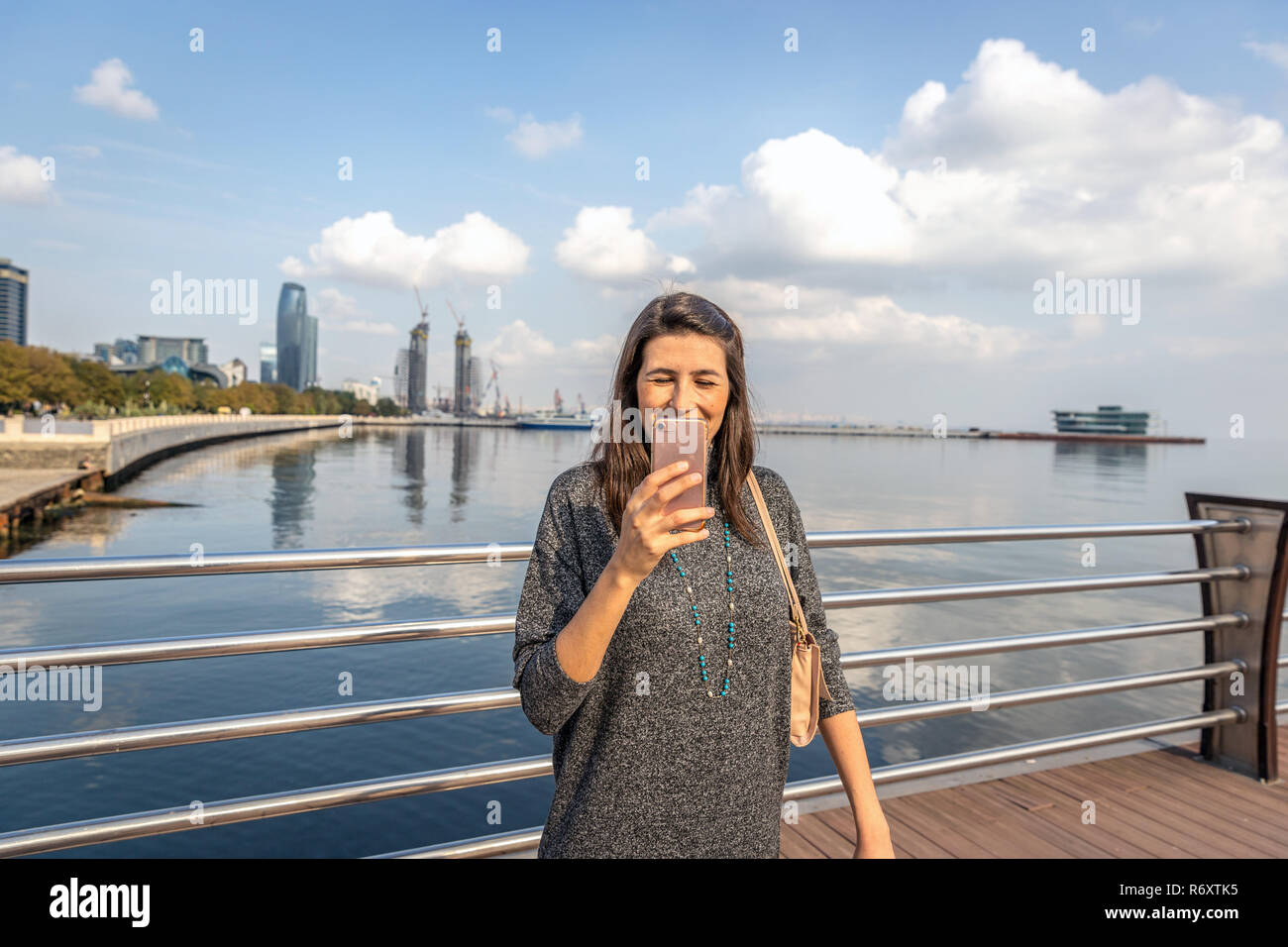 Baku in Azerbaijan - Oct 12th 2018 - una giovane donna con un sorriso in faccia tenendo un cellulare foto di Baku, capitale dell'Azerbaigian Foto Stock