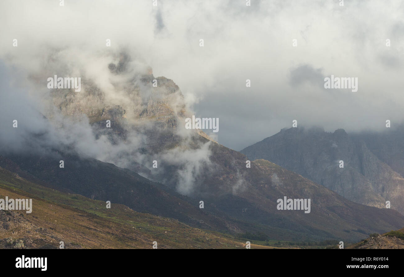 Paesaggio di montagne e drammatica nuvole appendere intorno alla parte superiore durante un giorno di pioggia in autunno in Du Toitskloof area Foto Stock