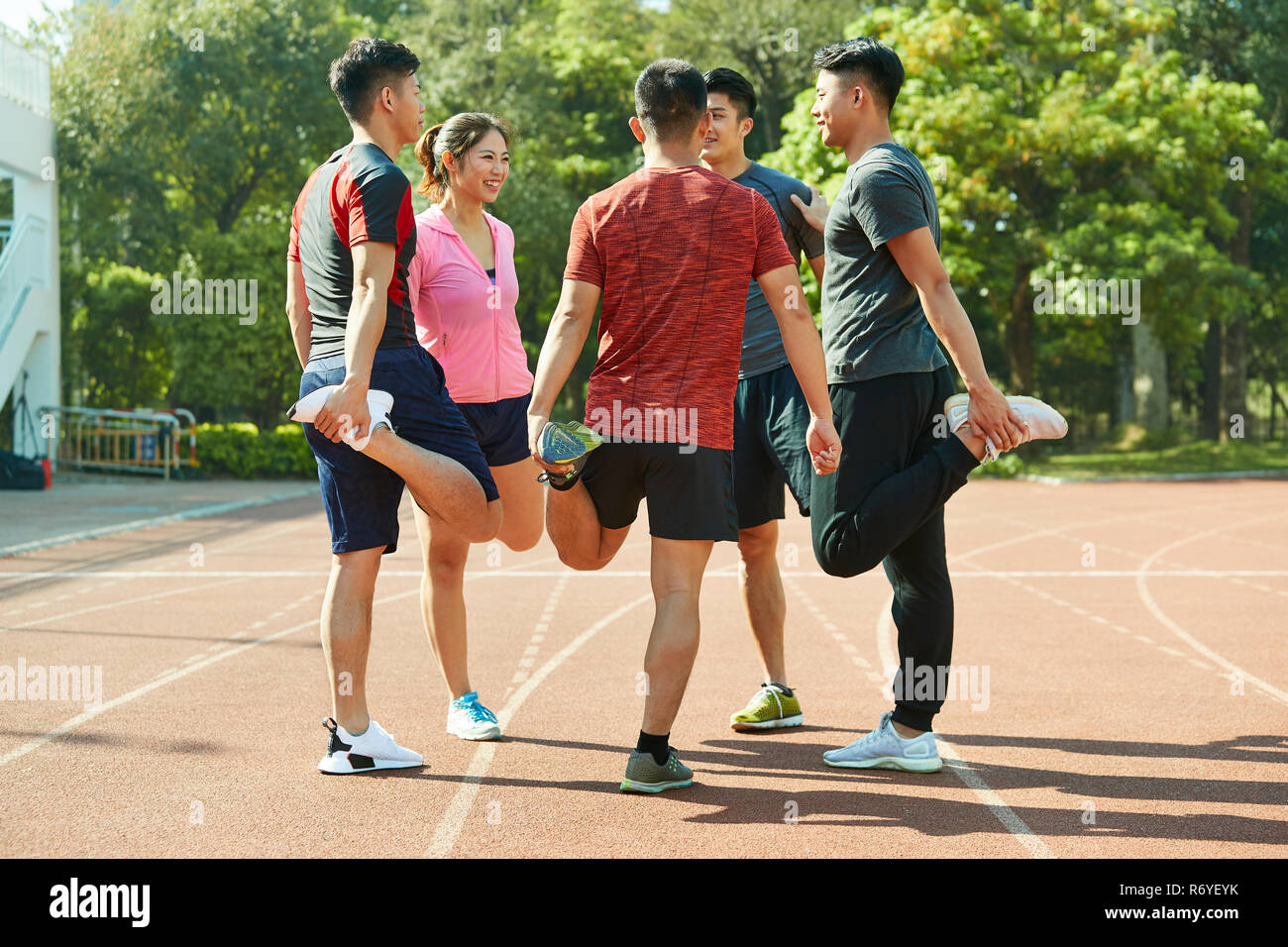 Un gruppo di giovani atleti asiatici stretching gambe sulla via ottenere pronto per la formazione. Foto Stock