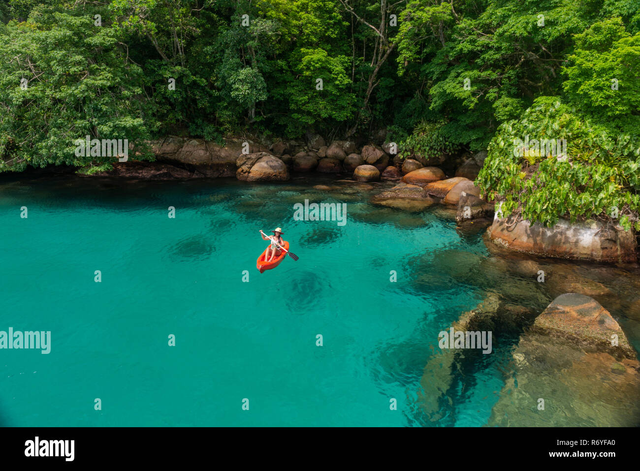 Una ragazza pagaie un kayak in acque chiare di Paraty, SE IL BRASILE Foto Stock