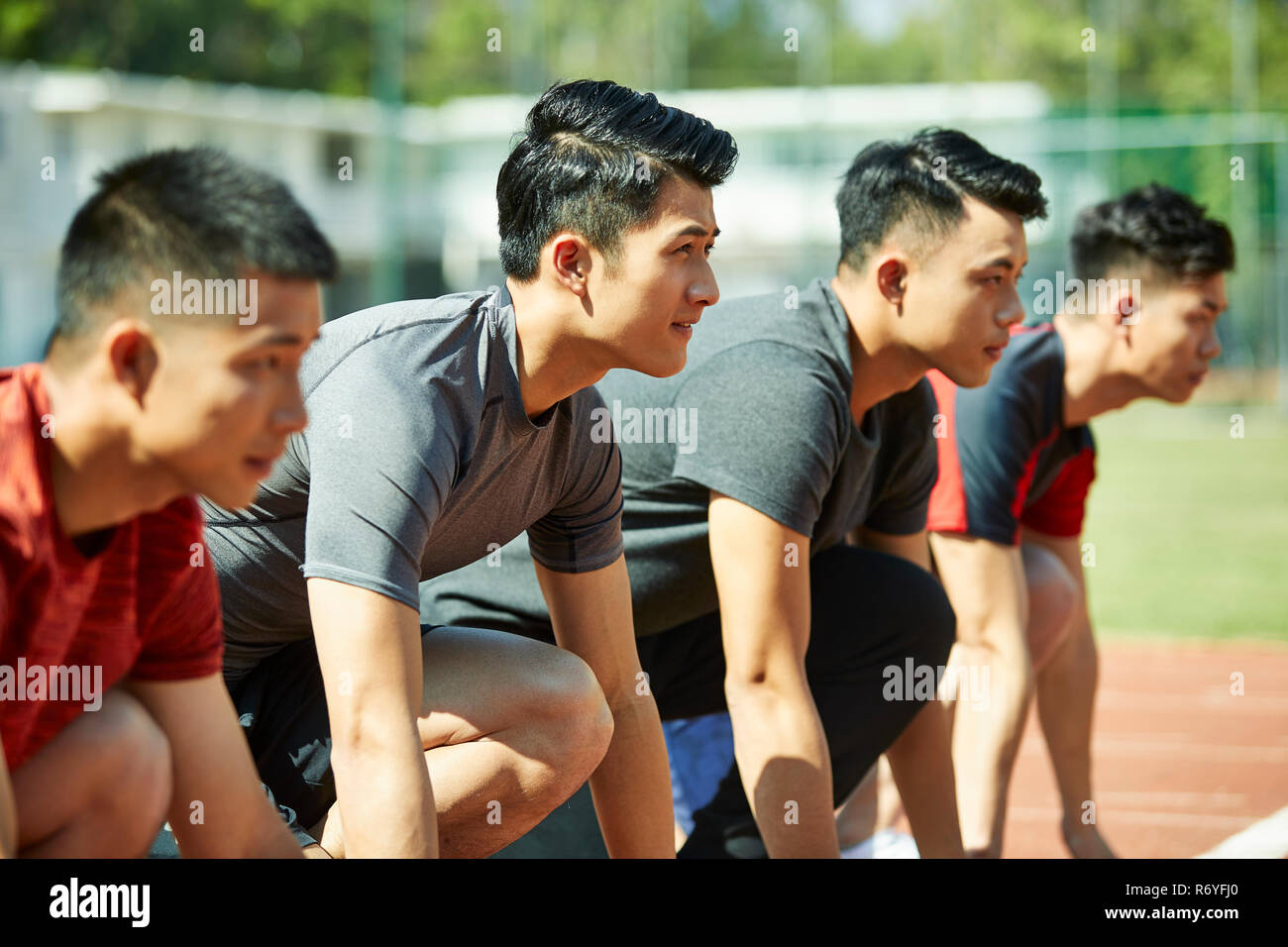 Giovani asiatici via e agli atleti velocisti impostazione sulla linea di partenza. Foto Stock