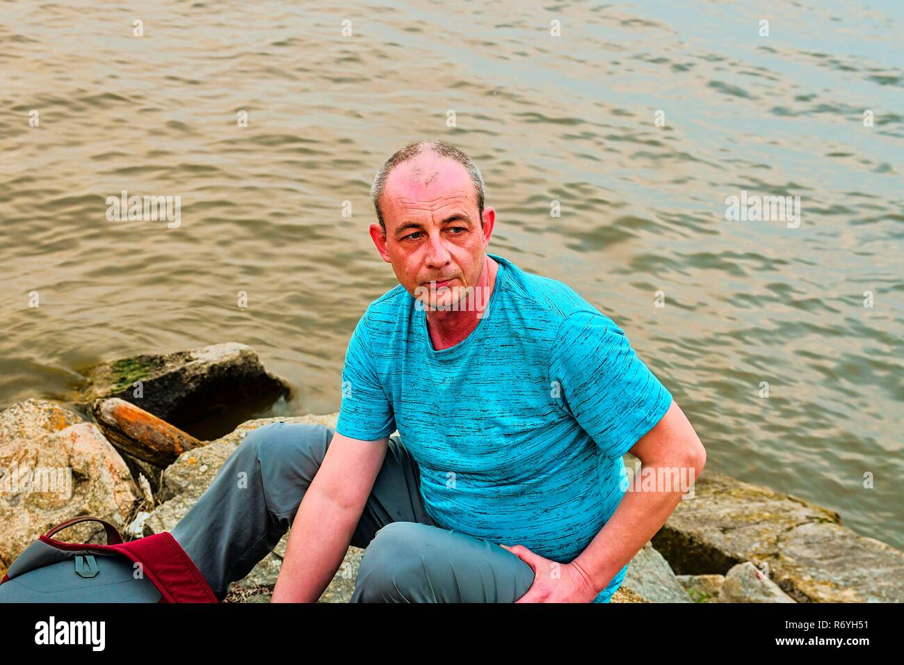 Midle invecchiato uomo seduto sulla riva del lago. Solitudine uomo maturo seduto sulla banca. Concetto di solitudine Foto Stock