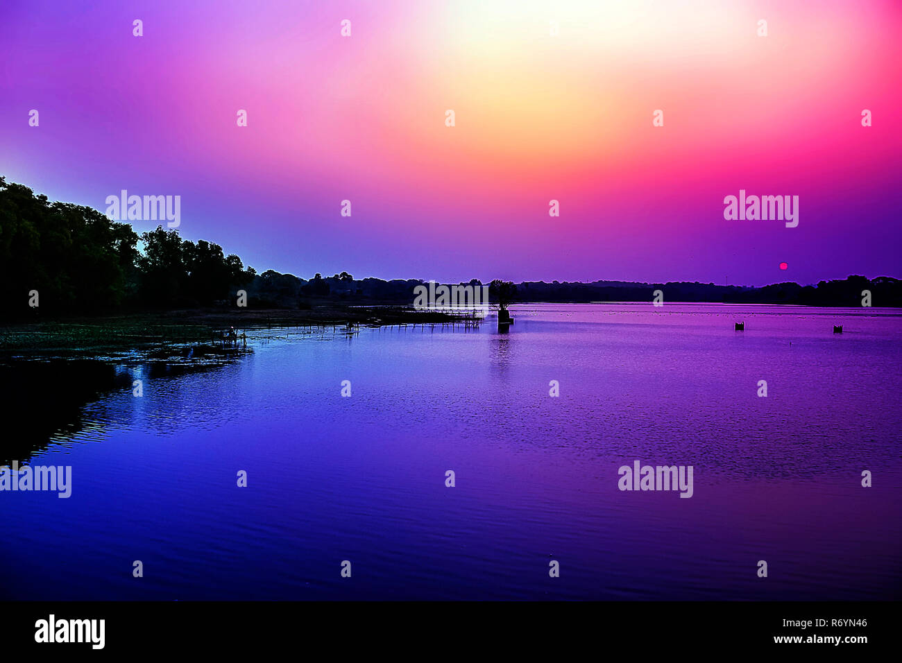 Acqua che riflette il sognante Cielo di tramonto in riva del fiume. Foto Stock