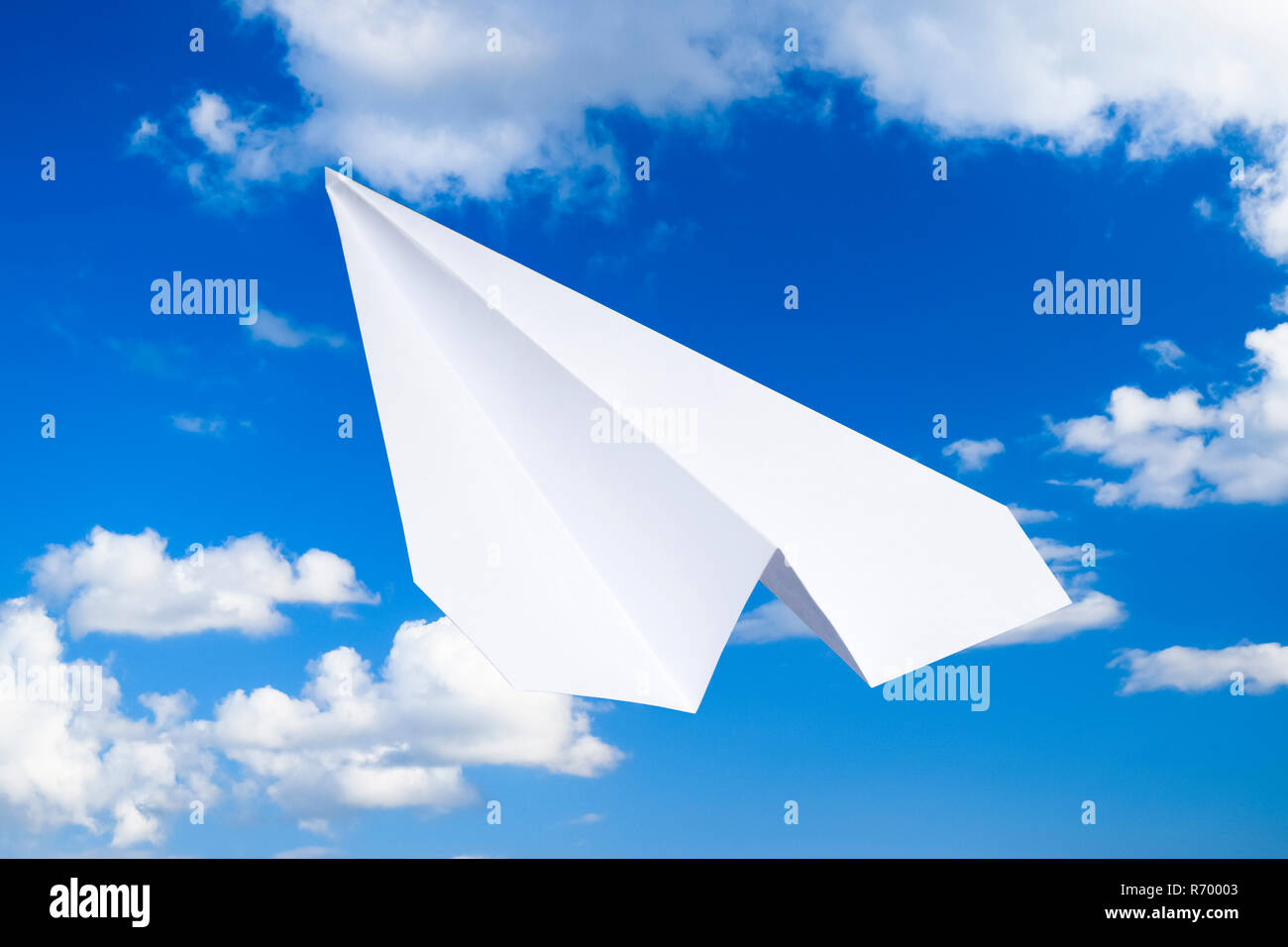 White aeroplano di carta in un cielo blu con nuvole. Il simbolo del messaggio in messenger Foto Stock