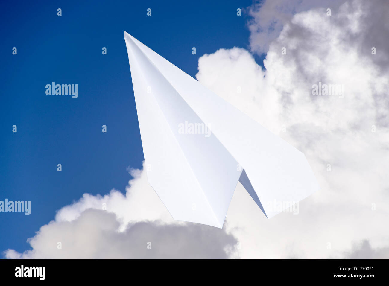 White aeroplano di carta in un cielo blu con nuvole. Il simbolo del messaggio in messenger Foto Stock