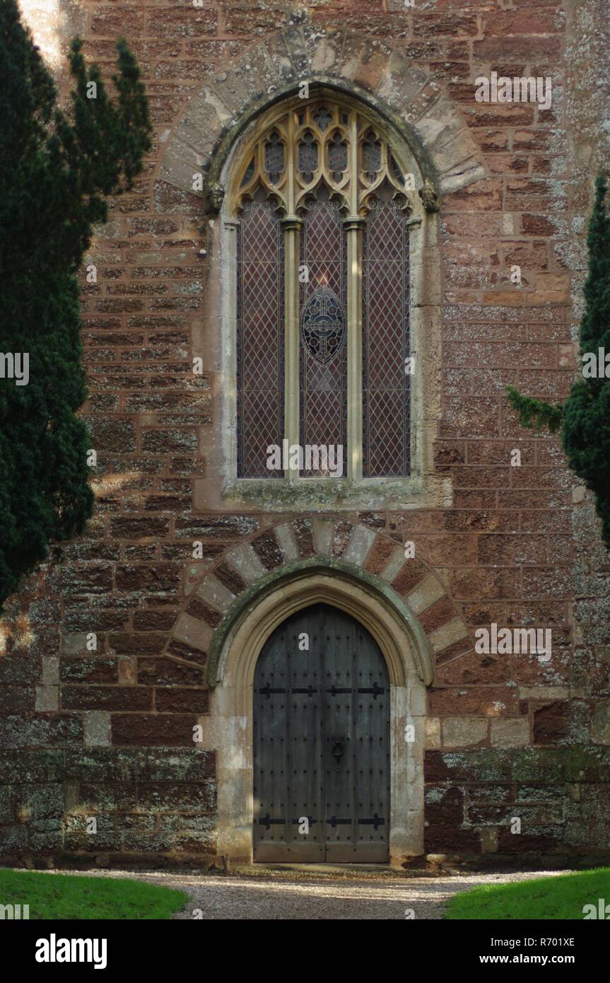 San Clemente chiesa parrocchiale, Powderham, Devon, Regno Unito. Finestra gotica e principale porta quercino in Torre Rossa, medievale di architettura ecclesiastica. Foto Stock