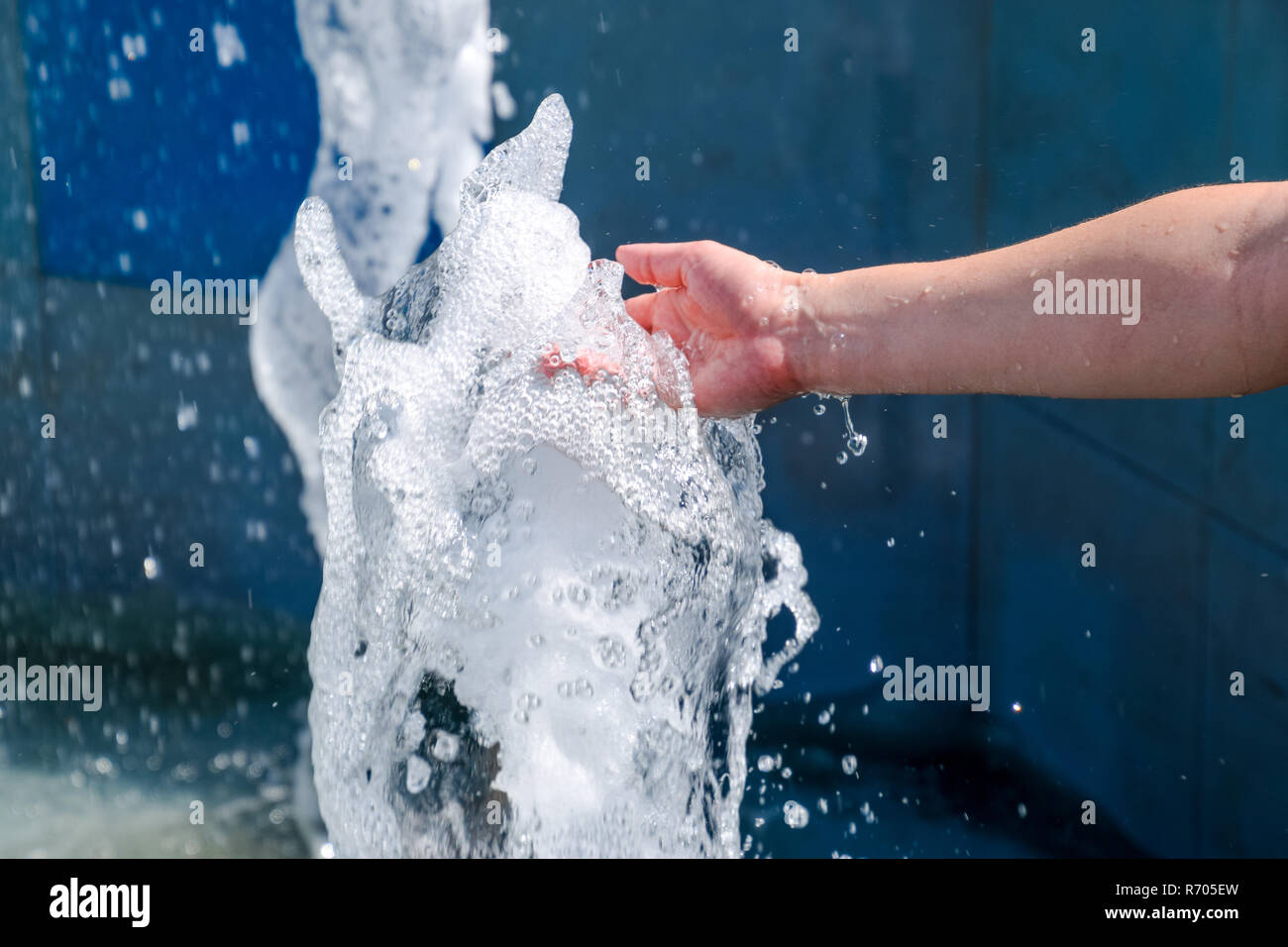 La mano toccare la fontana. Un flusso di acqua dalla fontana è toccato a mano Foto Stock