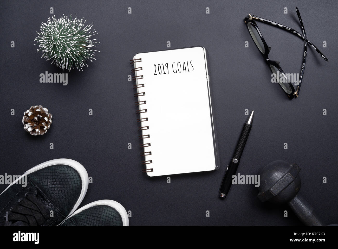 2019 nuovi anni di risoluzioni sport piatto composizione laici. Scarpe nero, nero manubri, bicchieri, vuoto portatile e la decorazione di Natale su nero backgro Foto Stock