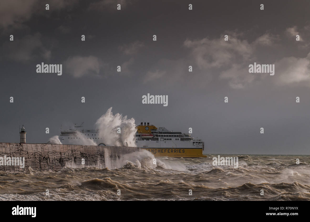 Newhaven, East Sussex, Regno Unito. 7th dicembre 2018. Il traghetto Transmanche per Dieppe parte, a poppa, la protezione delle mura del porto di Newhaven nel mare mosso dal vento. Forte vento squally da ovest con pioggia pesante ma ancora unseasonably caldo a 10 C. Foto Stock