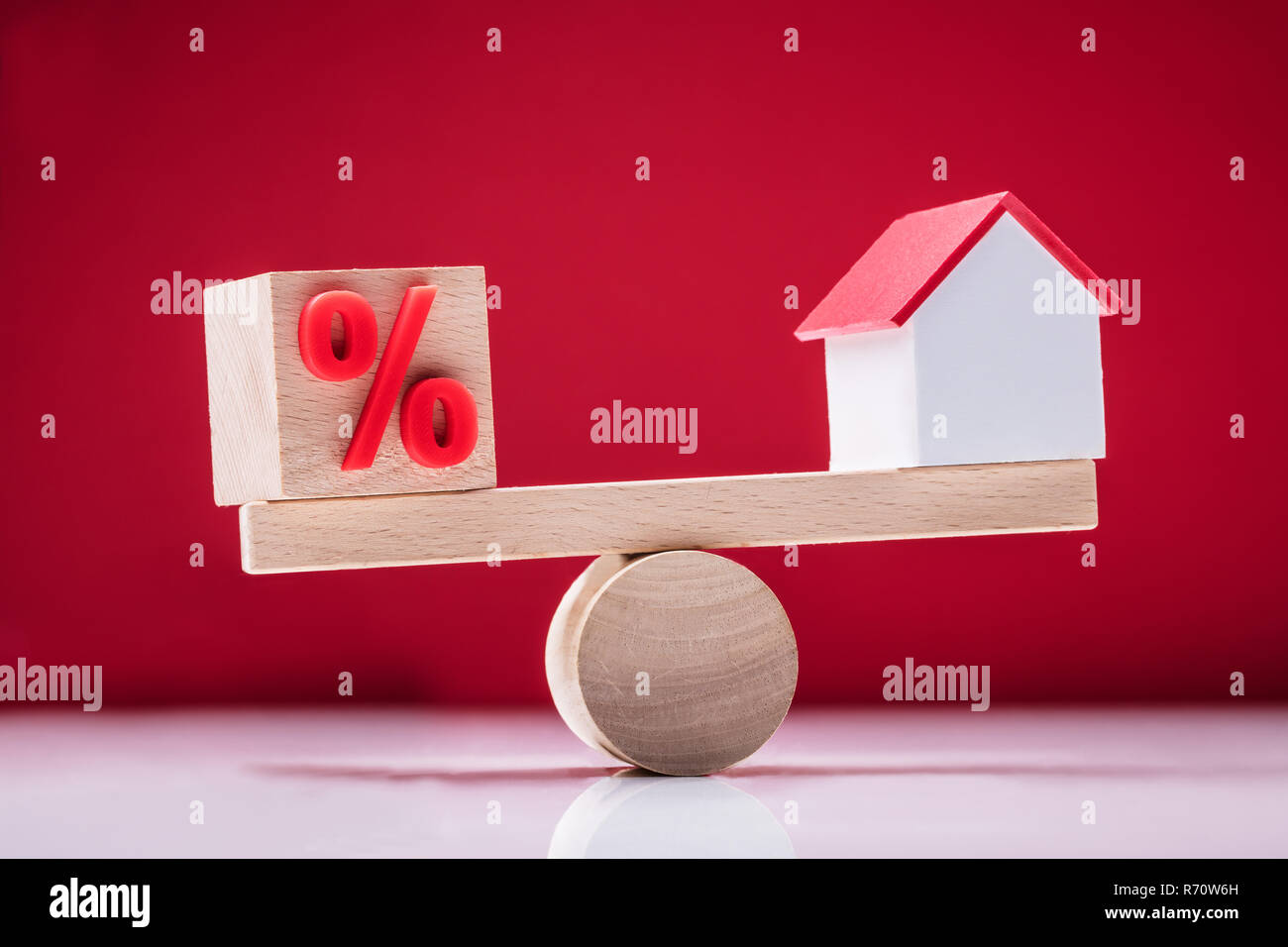 Altalena che mostra l'equilibrio tra il simbolo di percentuale e modello di casa Foto Stock