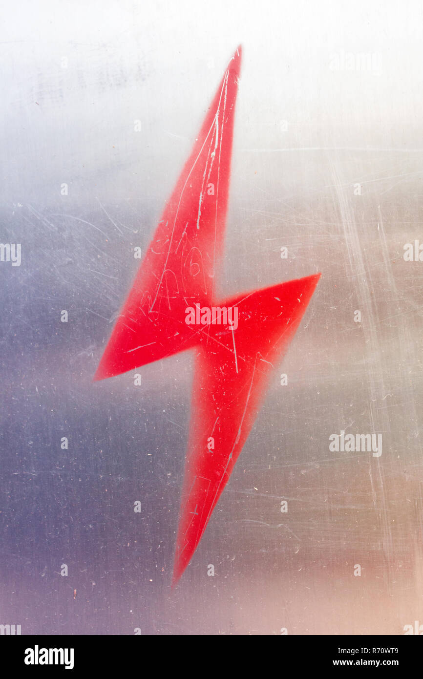 Elettricità segno di avvertimento su sfondo metallico. Fulmine rosso Foto Stock