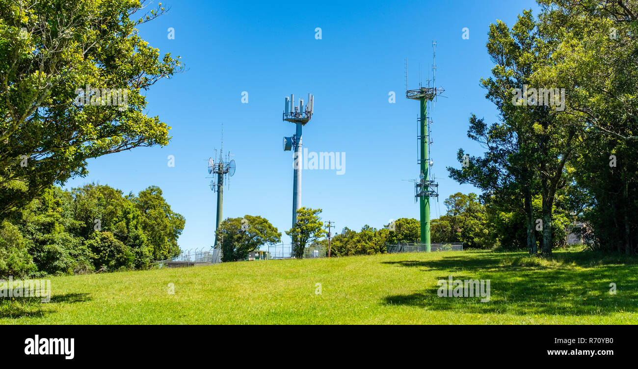 Montanti di telecomunicazione con antenna TV e telefono mobile trasmettitore in loco di bellezza del paesaggio con alberi contro un cielo blu in Australia Foto Stock