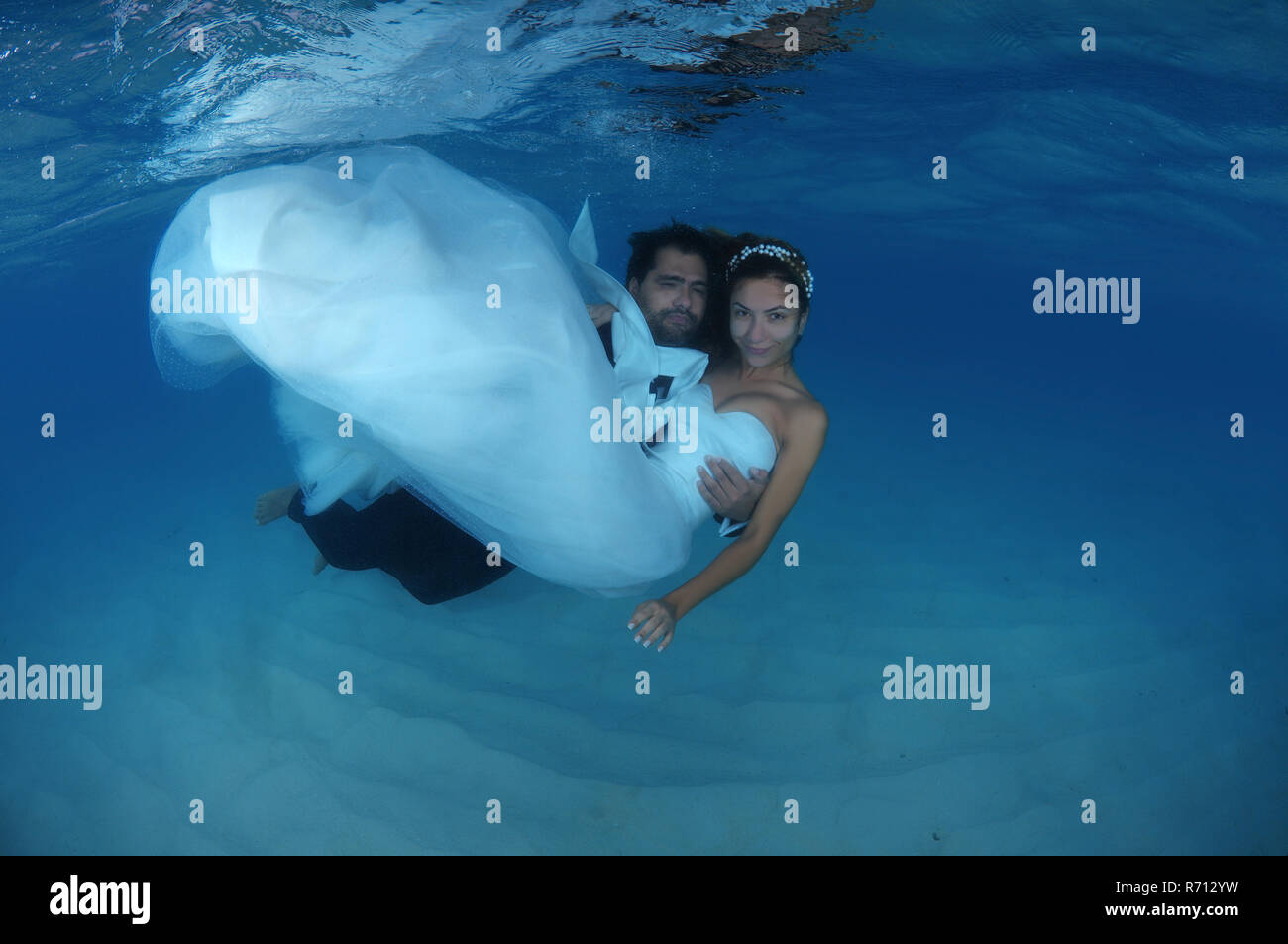Lo sposo tenendo la sposa nelle sue braccia subacquea, Oceano Indiano, Maldive Foto Stock