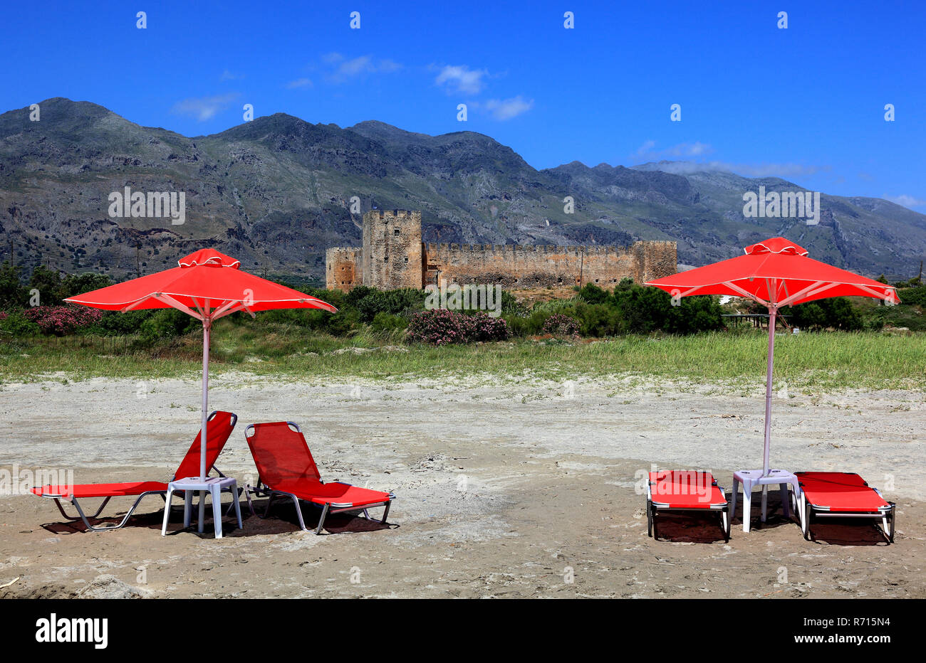 Rosso di ombrelloni e sedie a sdraio di fronte Frangokastello castle, Creta, Grecia Foto Stock