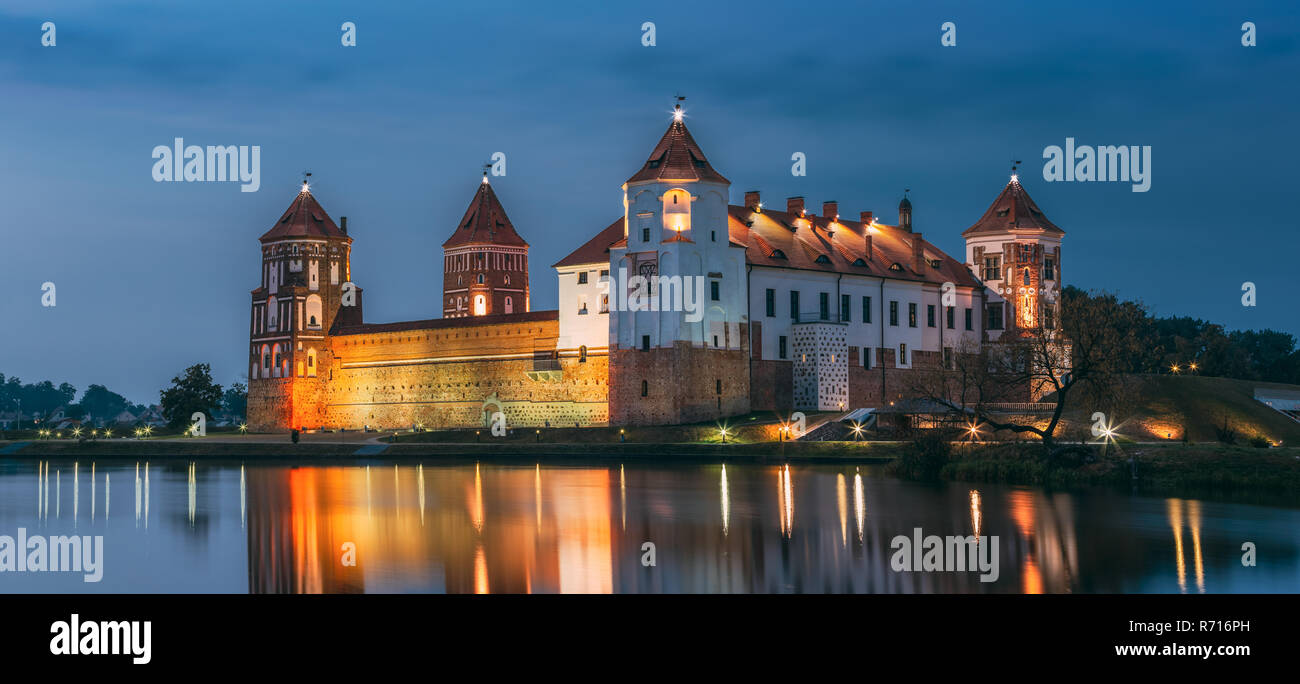 Mir, Bielorussia. Vista panoramica del complesso del Castello di Mir In illuminazione serale con candelette di riflessioni sul lago di acqua. UNESCO Patrimonio dell'Umanità. Famoso punto di riferimento, un Foto Stock